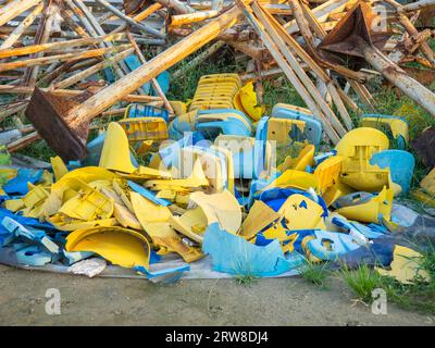 Vecchie sedie di plastica rotte allo stadio. Concetto di rivolta dei fan. Un mucchio di sedie di plastica. Rotto e abbandonato. Sedie gialle e blu Foto Stock