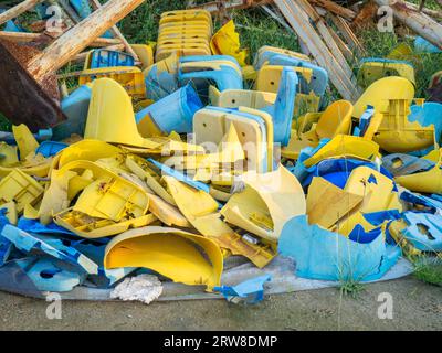 Vecchie sedie di plastica rotte allo stadio. Concetto di rivolta dei fan. Un mucchio di sedie di plastica. Rotto e abbandonato. Sedie gialle e blu Foto Stock