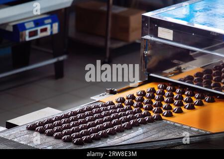 Processo di lavorazione dei marshmallow con glassa al cioccolato in pasticceria su macchina trasportatore, primo piano. Foto Stock