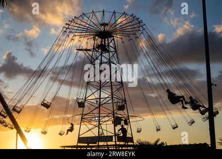 Batumi, Georgia. 09.10.2023 sagome di persone sulla giostra. Concetto di divertimento e intrattenimento. Persone su caroselli al tramonto. Città di villeggiatura. Lunap Foto Stock