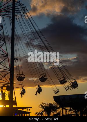 Sagome di persone sulla giostra. Concetto di divertimento e intrattenimento. Persone su caroselli al tramonto. Città di villeggiatura. Lunapark. Adrenalina. Speed carous Foto Stock