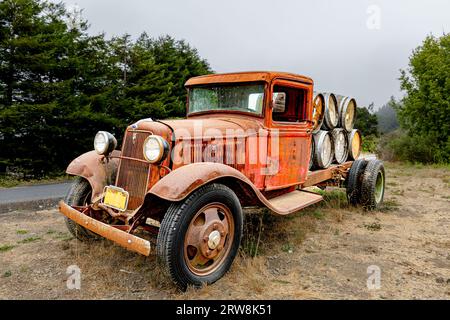 Rusty vecchio camion abbandonato seduto in campo con botti di vino di quercia sul pianale. Foto Stock