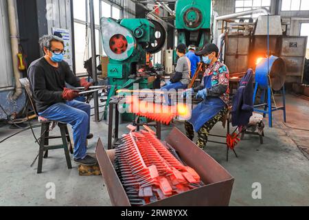 CONTEA DI LUANNAN, Cina - 24 settembre 2021: I lavoratori lavorano intensamente su una linea di produzione di forgiatura in uno stabilimento di produzione di utensili hardware nel nord della Cina Foto Stock