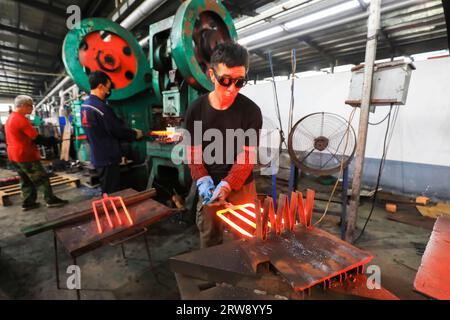 CONTEA DI LUANNAN, Cina - 24 settembre 2021: I lavoratori lavorano intensamente su una linea di produzione di forgiatura in uno stabilimento di produzione di utensili hardware nel nord della Cina Foto Stock