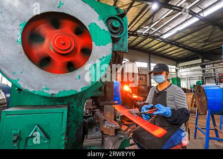 CONTEA DI LUANNAN, Cina - 24 settembre 2021: I lavoratori lavorano intensamente su una linea di produzione di forgiatura in uno stabilimento di produzione di utensili hardware nel nord della Cina Foto Stock