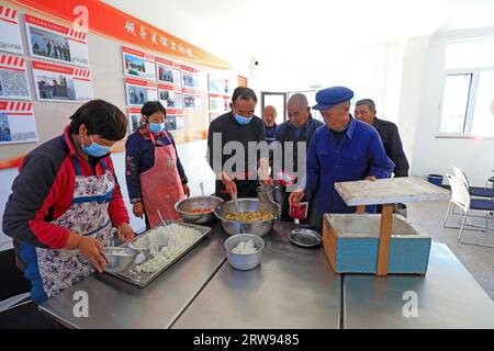 LUANNAN COUNTY, Cina - 11 ottobre 2021: Il personale di cucina della piccola mensa per anziani serve cibo e verdure per anziani, Chin Nord Foto Stock