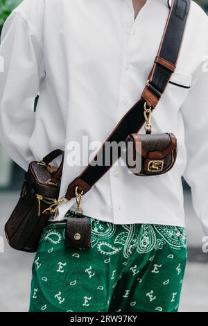 Milano, Italia - 19 giugno 2022: L'uomo indossa una mini borsa a spalla paisley marrone di Etro, Street style. Foto Stock