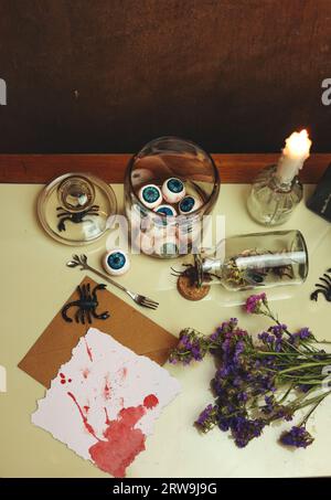 natura morta di halloween con una carta bianca e sanguinosa, palline oculari, scorpioni, insetti e fiori secchi Foto Stock