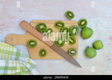 Mini kiwi, frutta intera e tagliata a metà su tavola di legno con coltello (Actinidia arguta) Foto Stock