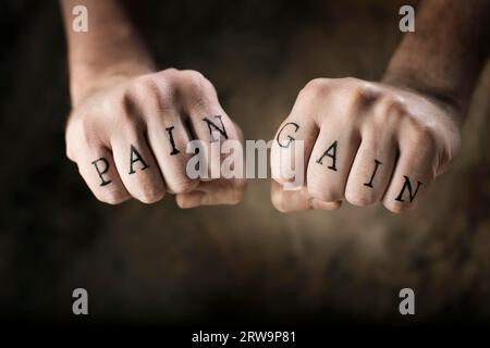 Uomo con tatuaggi finti dolore e guadagno sulle mani, riferendosi al motto dell'esercizio "No Pain, No Gain" Foto Stock