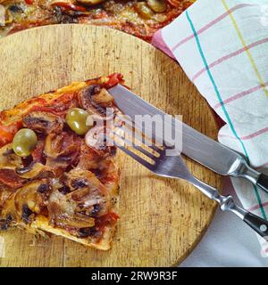 Una pizza appena sfornata con salame, pomodoro, formaggio, olive e funghi Foto Stock