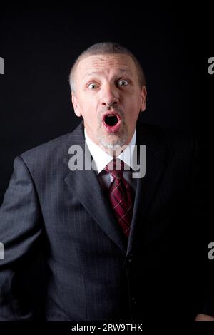 Uomo maturo emotivo che urla su sfondo nero Foto Stock