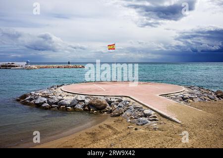 Eliporto sul Mar Mediterraneo con bandiera spagnola a Marbella, Costa del Sol, provincia di Malaga, Spagna Foto Stock