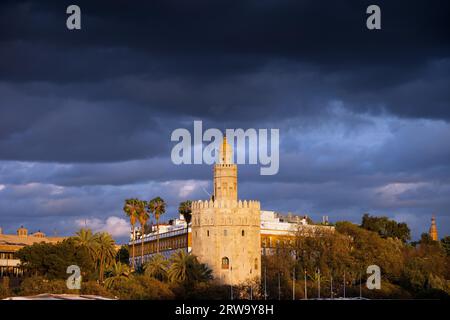 Torre del Oro al tramonto con nuvole di tempesta sopra, punto di riferimento medievale risalente all'inizio del XIII secolo a Siviglia, Spagna, regione dell'Andalusia Foto Stock