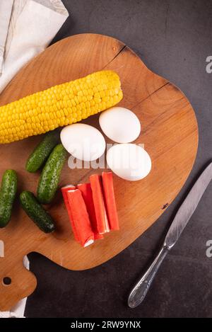 ingredienti per insalata di granchi: surimi, uova, mais, cetrioli e maionese di sause su tavola da kithen. Specialità di pesce. Foto Stock