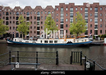 Edifici lungo il canale e la banchina di Entrepotdok ad Amsterdam, convertiti da vecchi magazzini in appartamenti, uffici, caffetterie in Olanda, Paesi Bassi Foto Stock