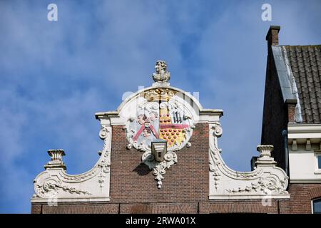 Colletto decorato in stile olandese con stemma in cima a una casa del XVII secolo nella città vecchia di Amsterdam, nei Paesi Bassi Foto Stock