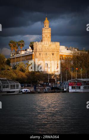 Torre dell'Oro (in spagnolo: Torre del Oro) di Siviglia bagnata dagli ultimi raggi del sole che tramonta prima della tempesta, regione spagnola dell'Andalusia Foto Stock