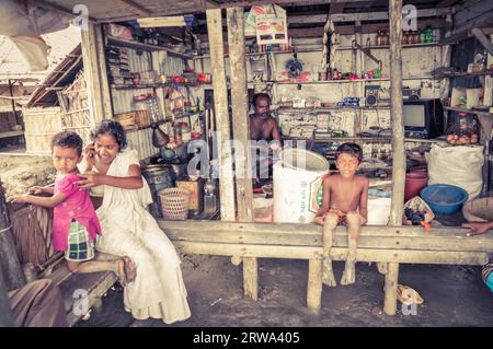 Sunderban, Bangladesh, circa luglio 2012: Famiglia nativa siede nella loro casa e i bambini scalzi guardano alla macchina fotografica a Sunderban, Bangladesh. Foto Stock