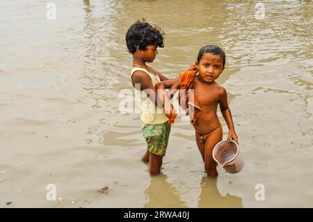 Sunderban, Bangladesh, circa luglio 2012: Due piccoli ragazzi con un lavaggio dei capelli neri nel fiume e un ragazzo tiene secchio a Sunderban, Bangladesh. Documentario Foto Stock