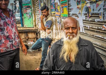 Dhaka, Bangladesh, circa luglio 2012: Vecchio uomo calvo con la barba lunga bianca fuma sigarette e disprezzi alla macchina fotografica in strada a Dacca, Bangladesh. Foto Stock