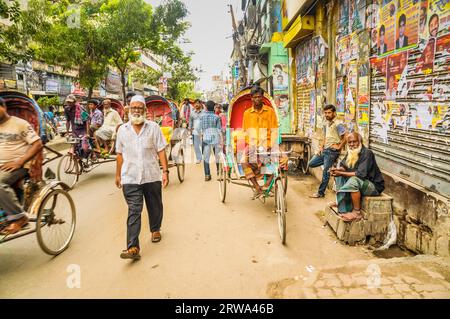 Dhaka, Bangladesh, circa luglio 2012: Persone che camminano e persone su risciò corrono in strade trafficate e guardano alla macchina fotografica a Dacca, Bangladesh. Foto Stock