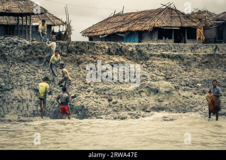 Sunderban, Bangladesh, circa luglio 2012: Uomini nativi lavorano nel fango vicino alle loro case e al fiume a Sunderban, Bangladesh. Documentario editoriale Foto Stock