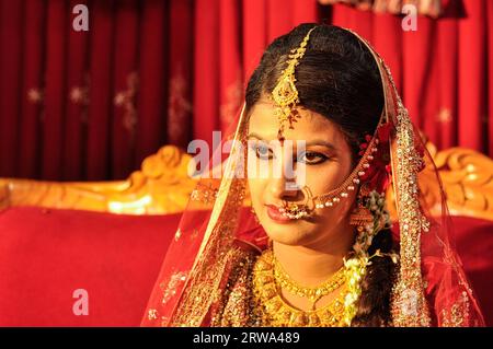 Dhaka, Bangladesh, circa luglio 2012: Giovane sposa dai capelli neri con piercing nel naso indossa un velo rosso scintillante sulla testa durante il suo matrimonio a Dacca Foto Stock