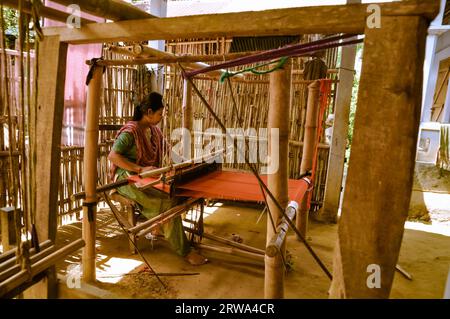 Srimongal, Bangladesh, circa luglio 2012: Una giovane donna dai capelli neri siede e tesse su un semplice telaio di legno a Srimongal, Bangladesh. Documentario editoriale Foto Stock