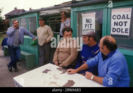 Sciopero dei minatori, Shirebrook, Derbyshire.1984 a Shirebrook Colliery colpisce i minatori passano l'ora del giorno presso il loro ufficio sciopero locale. Le mogli dei minatori all'interno si sono riunite per dare sostegno ai loro uomini e fornire pacchi di cibo per quei minatori che ne hanno bisogno. Gli avvisi nelle finestre degli uffici locali dell’unione proclamano «carbone il futuro dell’energia delle Nazioni. Salvalo con num. Carbone non Dole." 1980S UK HOMER SYKES Foto Stock