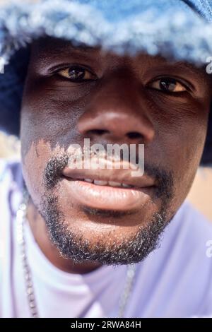 Primo piano estremo del giovane uomo nero che guarda la fotocamera all'aperto Foto Stock