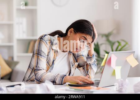 Una giovane ragazza indiana stanca si arrabbia per il numero di compiti, sbriciola la carta e la getta via, cerca di calmarsi meditando. Stressante Foto Stock