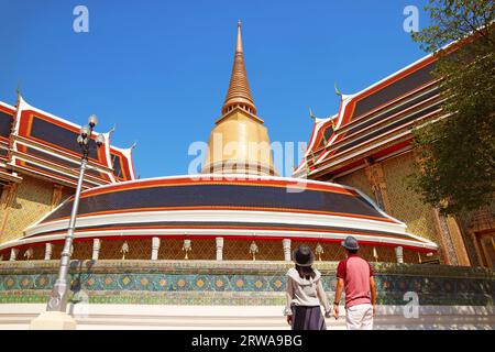 Coppia impressionata da una Pagoda dorata alta 43 metri e dall'iconica Galleria circolare del Tempio buddista di Wat Ratchabophit, Bangkok, Thailandia Foto Stock