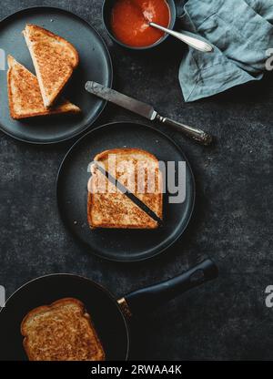 Vista dall'alto dei panini al formaggio grigliati e dello sfondo nero della zuppa. Foto Stock