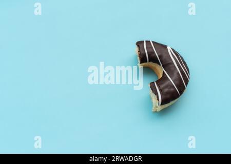 Ciambella al cioccolato disordinata isolata su sfondo blu, dopo alcune modifiche. Foto Stock