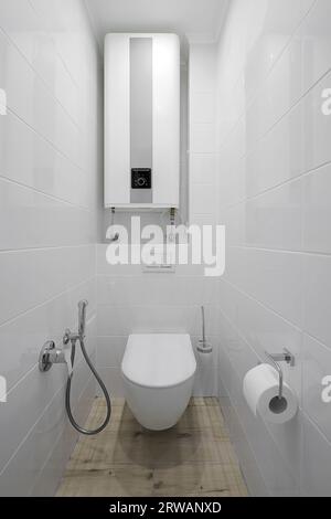 WC bianco con caldaia elettrica all'interno del bagno Foto Stock