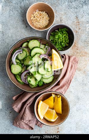 Vista dall'alto di un'insalata di cetrioli e cipolle rosse con noci tritate, erbe aromatiche e limone Foto Stock