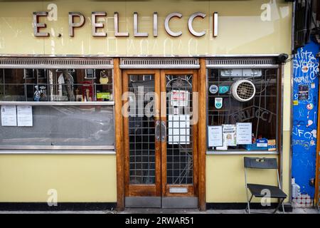 Scena di strada nell'East End, lungo Bethnal Green Road, dove molte piccole imprese e negozi indipendenti riforniscono l'area, tra cui questo caffè italiano E. Pellicci il 16 agosto 2023 a Londra, Regno Unito. Pelliccis è un caffè vintage Art Deco che offre colazione inglese completa e piatti classici italiani dal 1900. Foto Stock