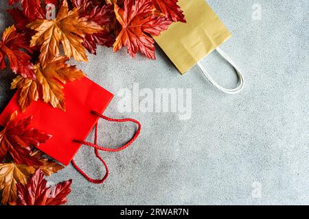 Vista dall'alto delle foglie di acero rosso autunnale sopra due sacchetti di carta bianca Foto Stock