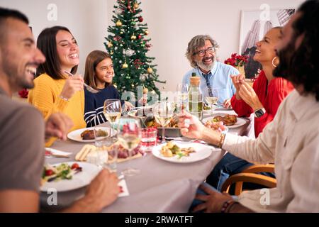 Divertente riunione di famiglia che celebra le vacanze di Natale insieme al tavolo delle feste. Le persone ridono. Foto Stock