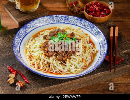 Spicy rosso zuppa di manzo spaghetti in una ciotola su tavolo di legno Foto Stock