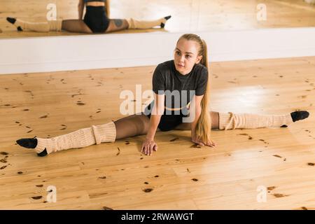 Giovane ballerina che si allunga e si allena in studio di danza - concetto di balletto e ballerina Foto Stock