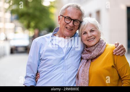 Ritratto di una felice coppia anziana che si abbraccia in città Foto Stock