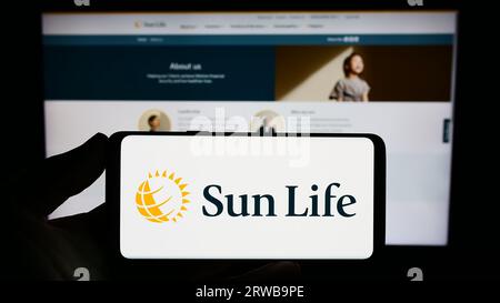 Persona che possiede uno smartphone con il logo della società canadese Sun Life Financial Inc. Sullo schermo davanti al sito Web. Concentrarsi sul display del telefono. Foto Stock