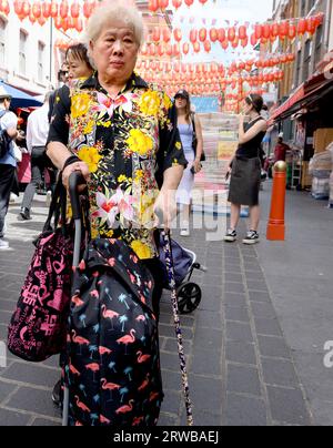 Londra, Regno Unito. Anziana donna cinese a Chinatown che indossa un luminoso top fiorito Foto Stock