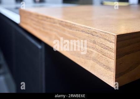 Primo piano macro messa a fuoco selettiva in legno incollato con frassino pieno sotto il bordo della vernice. Piano ripiano con ripiano dal design contemporaneo all'interno della cucina. Foto Stock