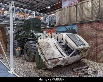 Un trattore a ruote medie Allis Chalmers che celara un'auto, una scena dell'Irlanda del Nord negli anni '1970, Royal Engineers Museum a Gillingham, Kent, Regno Unito. Foto Stock