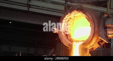 Processo di fusione dei metalli in altoforno in impianti o fabbriche metallurgici. Metallo fuso di ferro liquido versato in contenitori, background industriale pesante Foto Stock