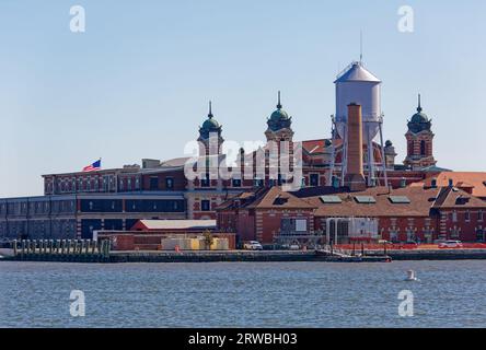Ellis Island vista dal Liberty State Park, New Jersey: L'edificio dei bagagli e del dormitorio si trova a sinistra dell'edificio principale (museo) a quattro torri. Foto Stock