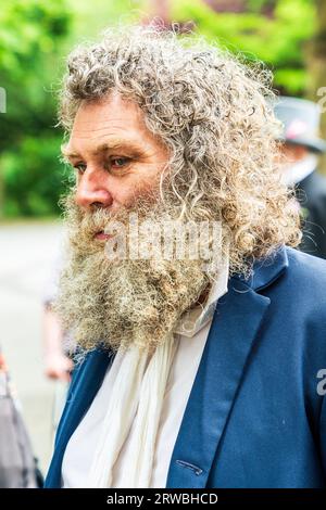 Foto della testa con vista laterale del viso di un uomo anziano con barba molto folta e capelli grigi ricci e disordinati al festival Broadstairs Dicken's. Foto Stock